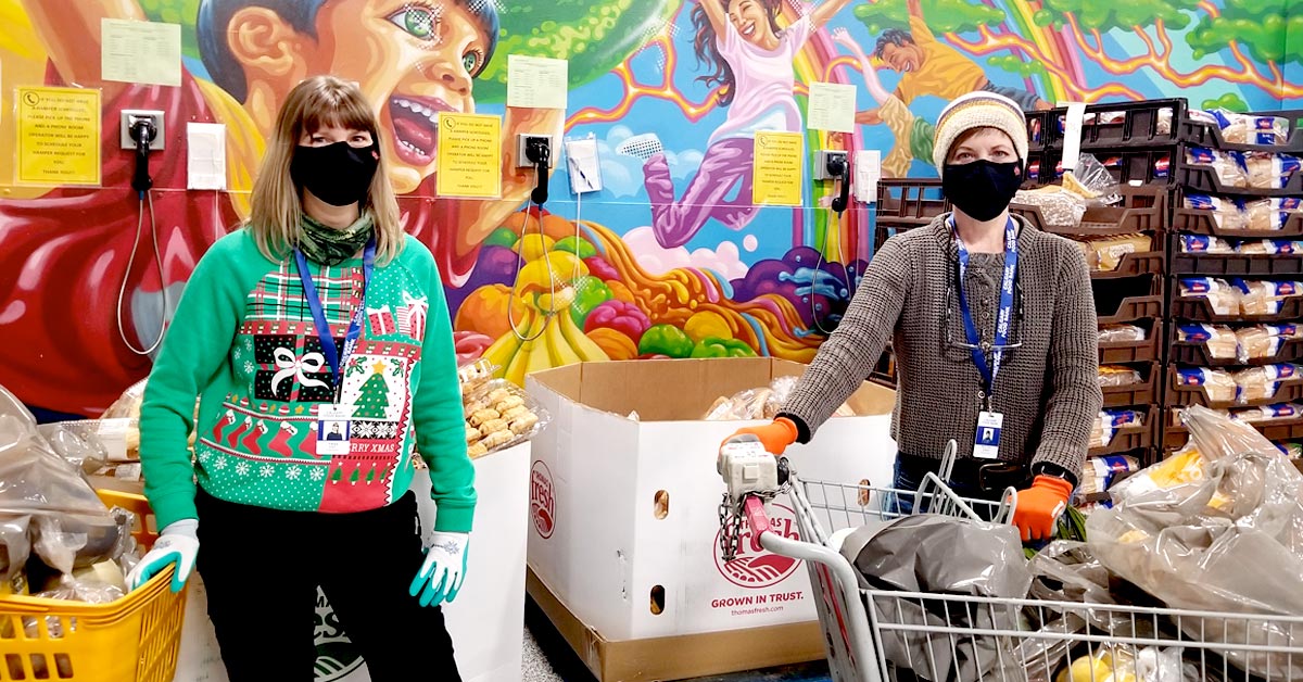 Volunteers standing with carts of food.