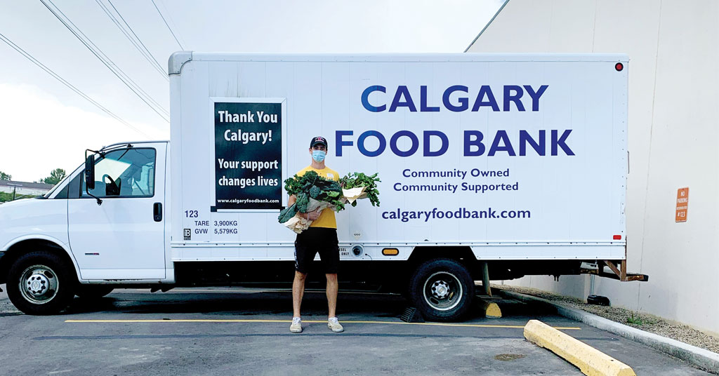 Man standing with an arm full of fresh green produce