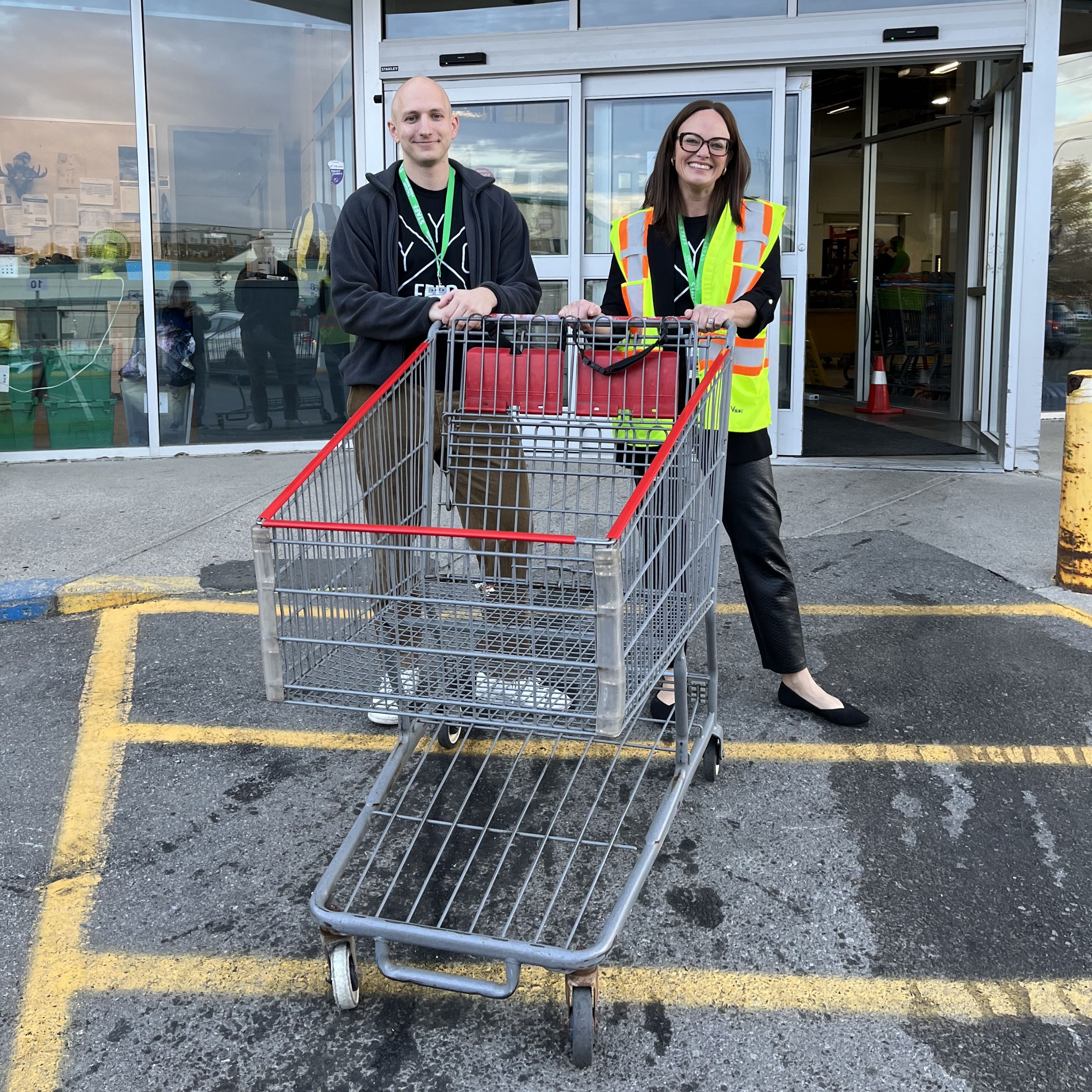 Robert and Melissa standing with an empty shopping cart after delivering the food to a client